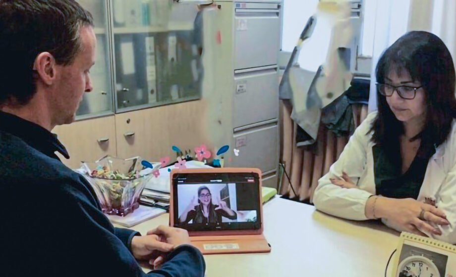 La foto rappresenta un medico posto di fronte ad un paziente sordo mentre utilizza il servizio di video interpretariato LIS allo IOV