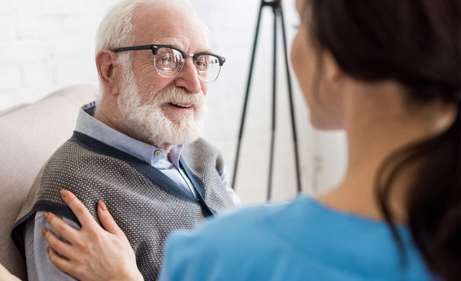 Un paziente anziano affetto da parkinson mentre un caregiver, da solo, gli appoggia la mano sulla spalla