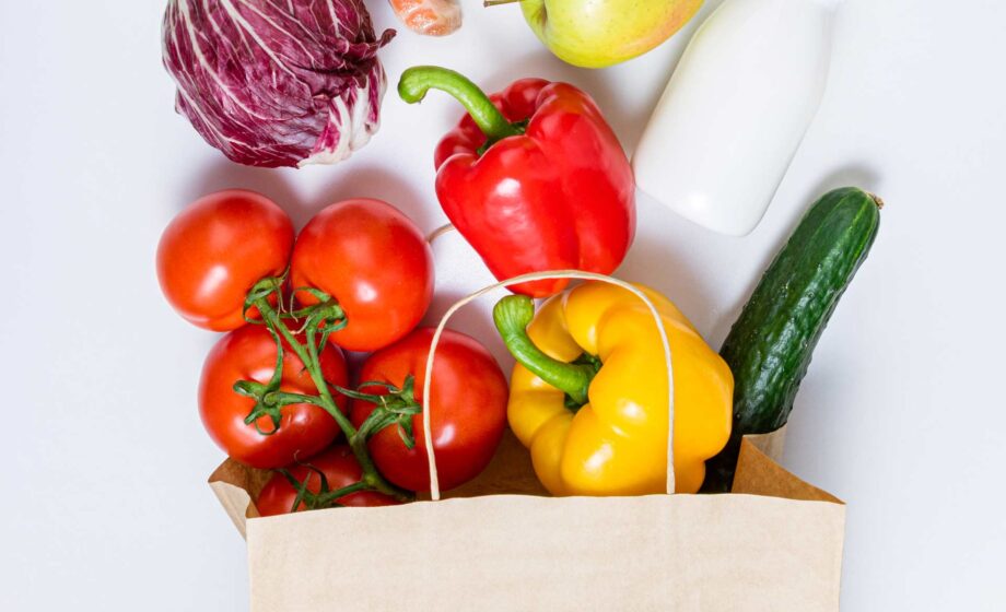Un sacchetto della spesa che contiene alimenti sani: pomodori, peperoni, zucchine, radicchio, mela